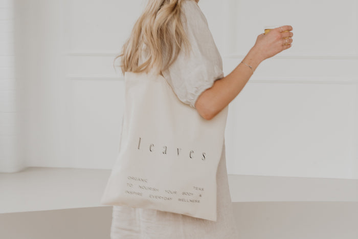 Blurred image of woman walking with a tote bag and tea in hand