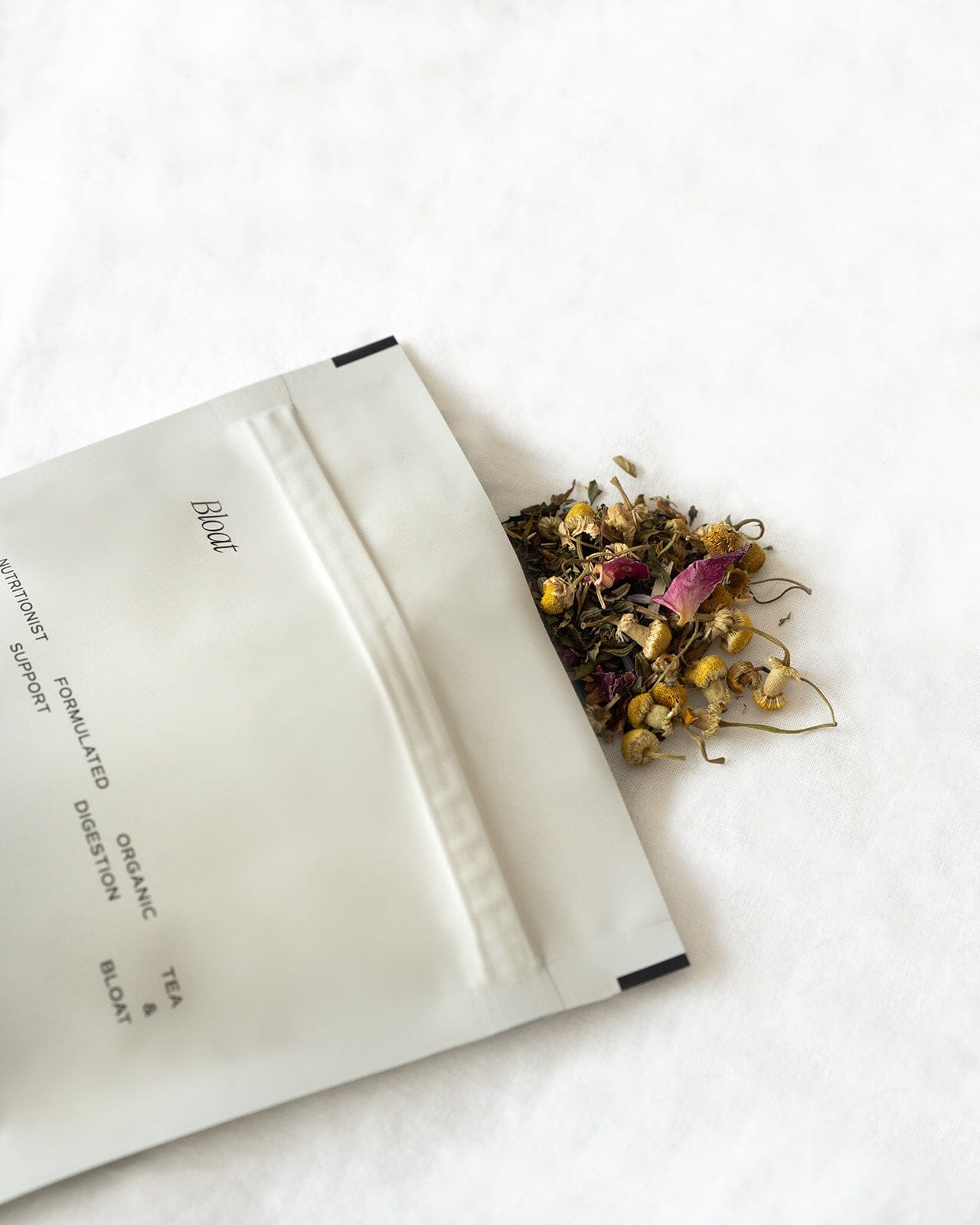 Bloat tea pouch laying down with tea spilling out 
