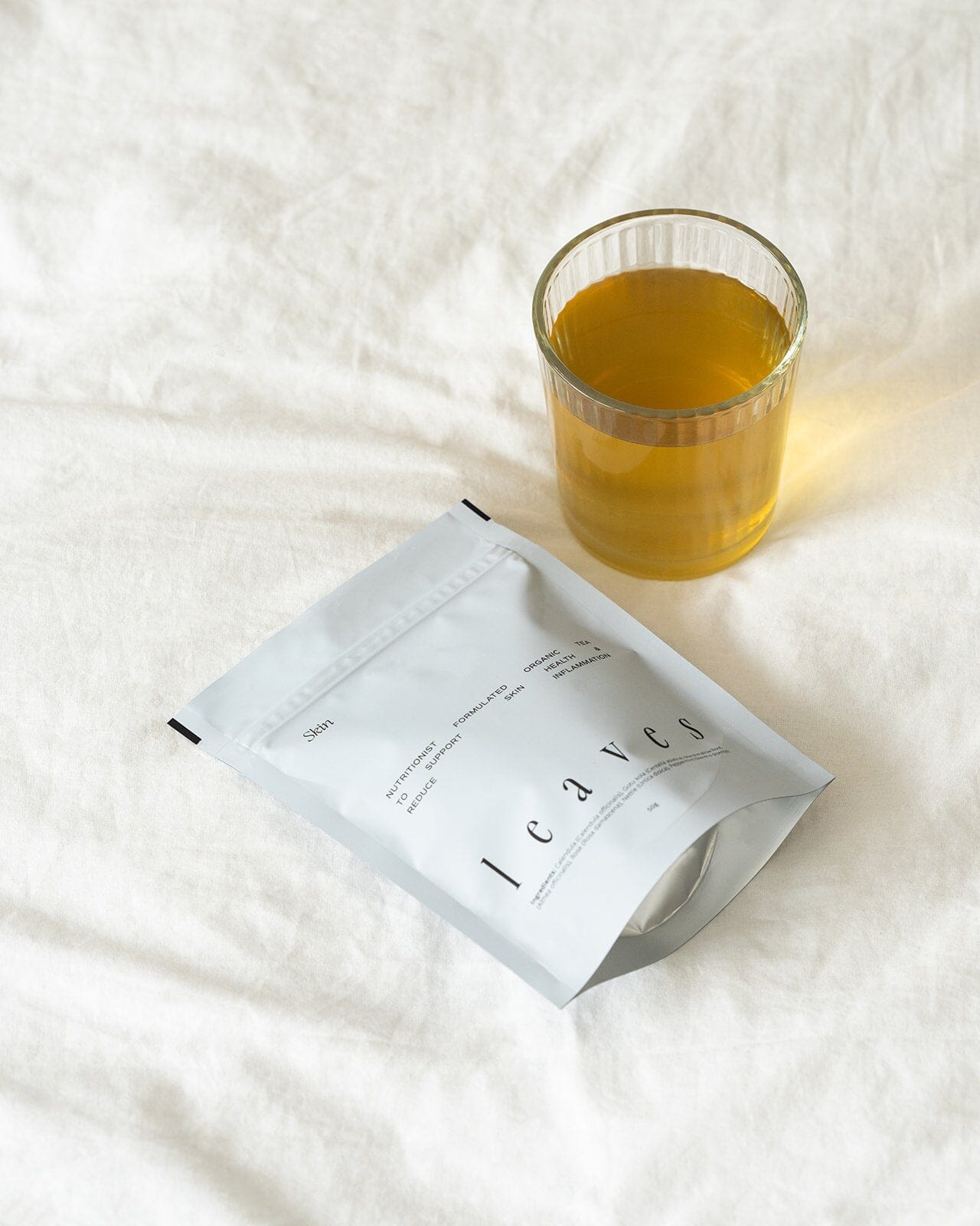 Skin leaves tea pouch laying down next to a cup of tea