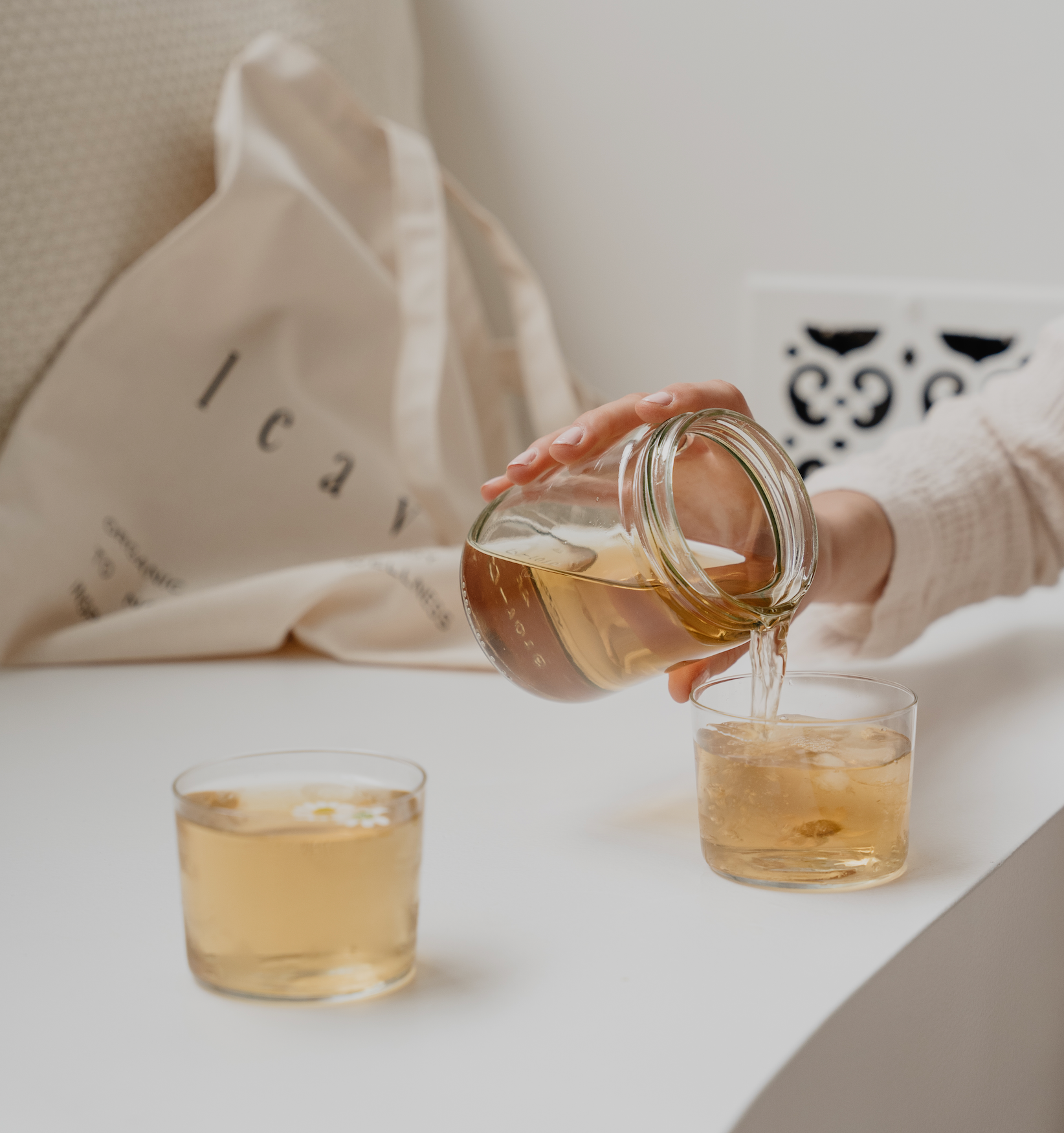 Woman's hand pouring tea from a mason jar into a clear cup