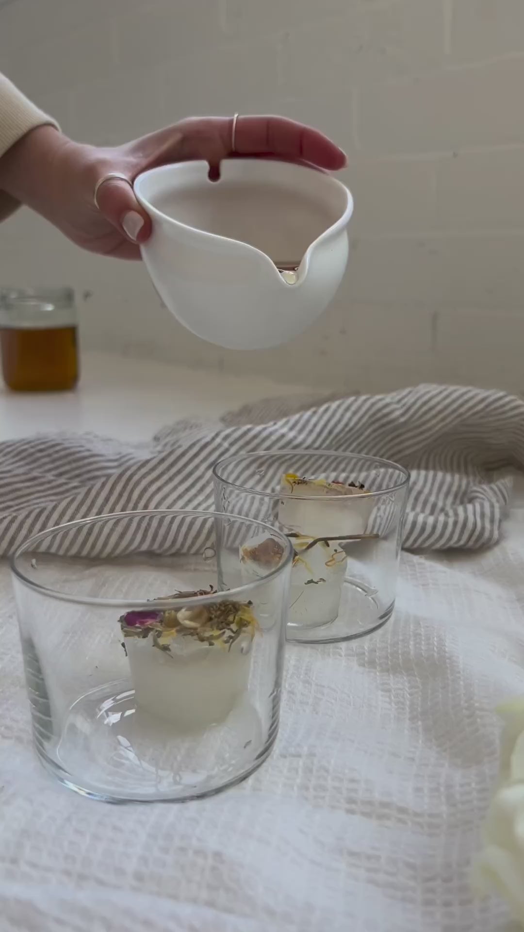 Woman's hand pouring tea into clear glasses with ice cubes